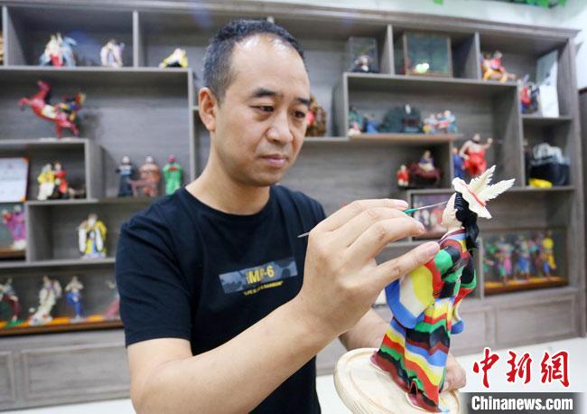 圖為安秋平正在創(chuàng)作代表隴南文縣民俗的《白馬人》作品?！「哒?攝