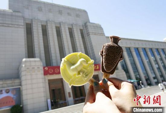 2021年7月30日，游客手拿“銅奔馬”“彩陶瓶”造型的雪糕，在甘肅省博物館前拍照打卡?！「哒?攝