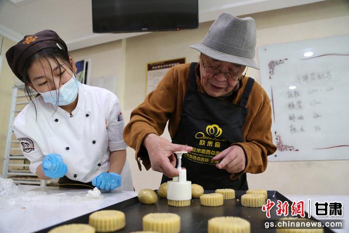 當日，受邀參加活動的臺胞臺屬代表、兩岸婚姻及子女、在甘臺商代表等歡聚一堂。圖為77歲的在甘臺胞潘天鑒制作月餅。九美旦增 攝
