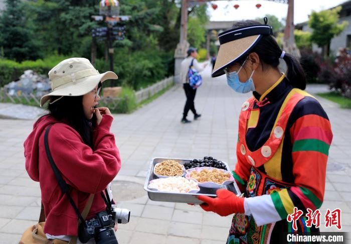 圖為身穿土族服飾的女性介紹當(dāng)?shù)靥厣〕?。　薛?攝