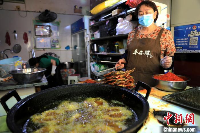 圖為平安驛·河湟民俗文化體驗(yàn)地內(nèi)的商戶炸干板魚(yú)。　薛蒂 攝