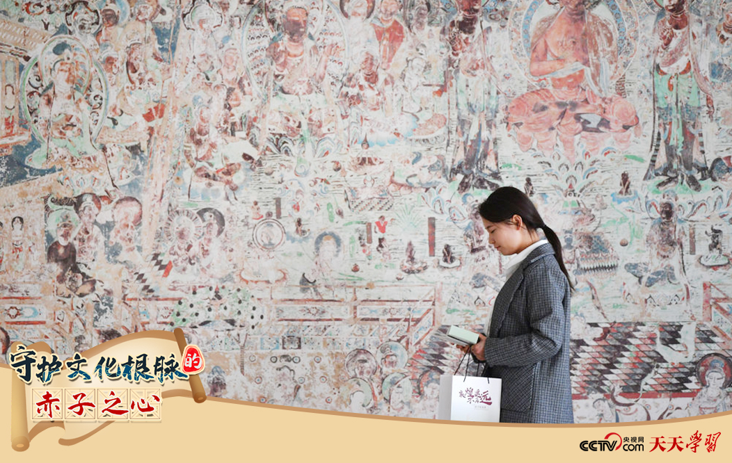 2023年4月25日，敦煌研究院文物數(shù)字化保護團隊創(chuàng)意營銷人員廖雪婷從一幅高保真復(fù)制壁畫前走過。
