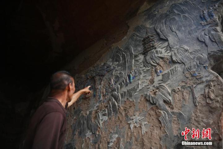 7月15日，甘肅省平?jīng)鍪袥艽h百里石窟長廊羅漢洞石窟內(nèi)，該窟文保員郭建平介紹窟內(nèi)石刻彩繪壁畫。郭建平家中三代人曾自發(fā)保護羅漢洞石窟。羅漢洞石窟遺存40余個窟龕，以北魏至清代風(fēng)格為主。中新社記者 李亞龍 攝