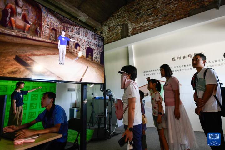 7月22日，游客體驗“尋境敦煌——數(shù)字敦煌沉浸展”后，在虛擬演播廳拍攝一段真人與洞窟虛擬場景交互的視頻。新華社記者 郎兵兵 攝</p>
<p>