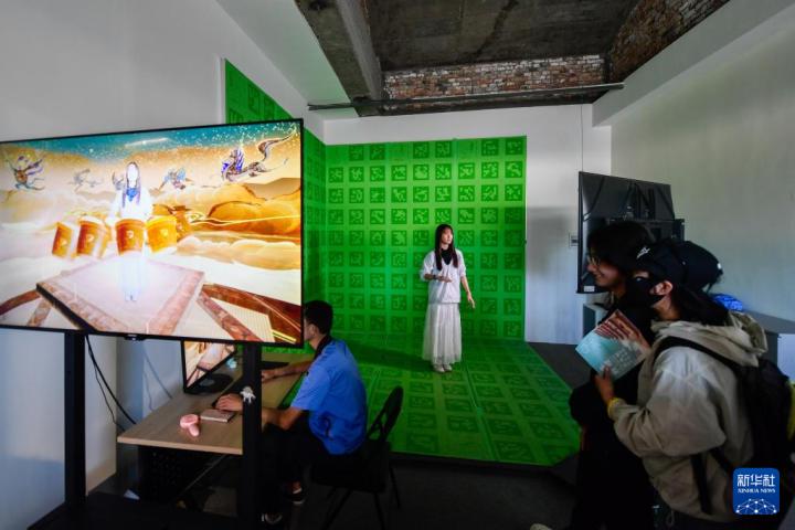 7月22日，游客體驗“尋境敦煌——數(shù)字敦煌沉浸展”后，在虛擬演播廳拍攝一段真人與洞窟虛擬場景交互的視頻。新華社記者 郎兵兵 攝</p>
<p>